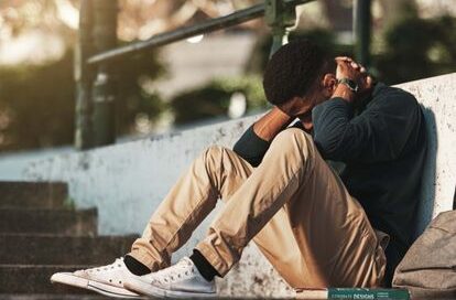 A man sitting down on the floor looking worried