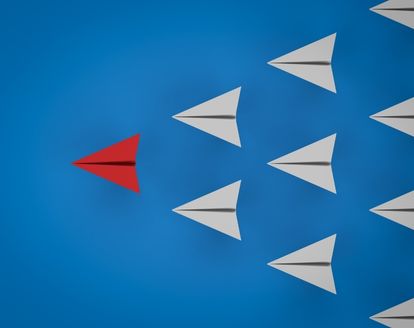 red paper plane leading the white paper planes